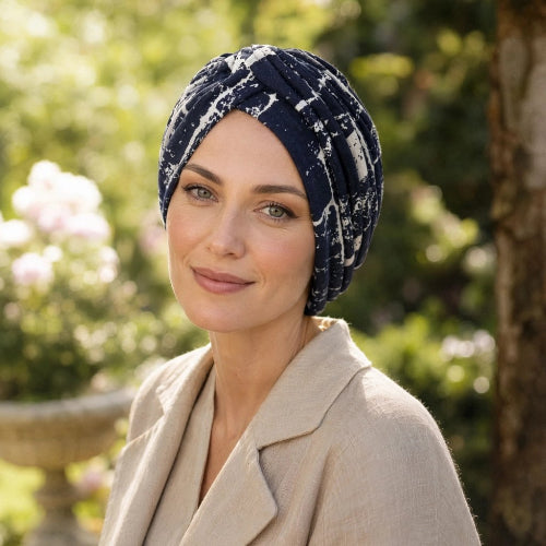Turban femme bleu marine a motifs blancs porte avec une veste beige dans un jardin