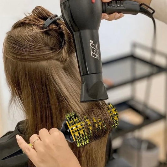 Brushing-avec-brosse-à-cheveux-bouclés-ronde-lissant-meche-brune-dans-salon-de-coiffure