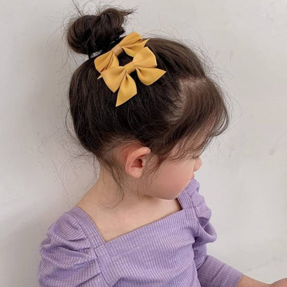 Pince-à-cheveux-jaune-sur-chignon-enfant-avec-haut-violet-style-mignon