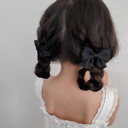 Pince-à-cheveux-noire-sur-deux-tresses-attachees-avec-grands-noeuds