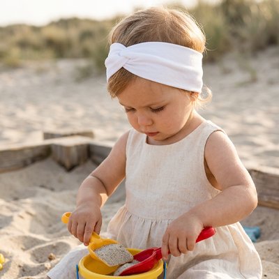 bandeau-cheveux-bébé-blanc-jouant-a-la-plage
