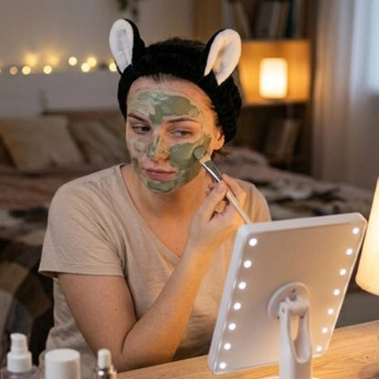 Bandeau maquillage noir oreilles de chat blanches femme applique masque visage vert avec pinceau devant miroir