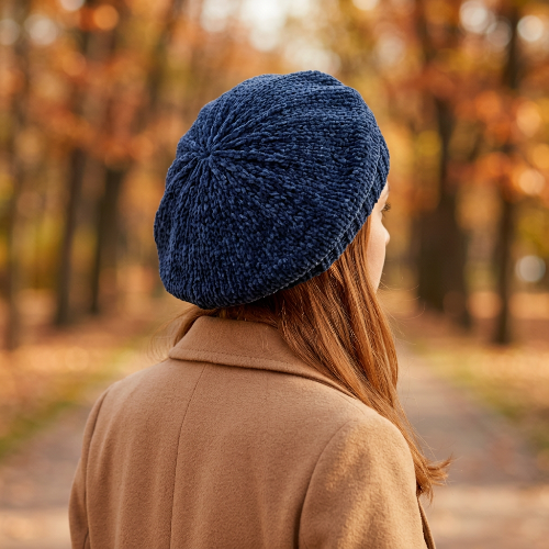 Béret bleu marine en chenille porte par une femme vue de trois quarts arriere montrant les mailles au sommet et le tombe du beret