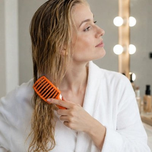 Brosse à cheveux orange demelante femme cheveux blond dans la salle de bain