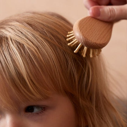 Brosse cheveux bébé a picots en bois utilisee sur les cheveux blonds d un enfant