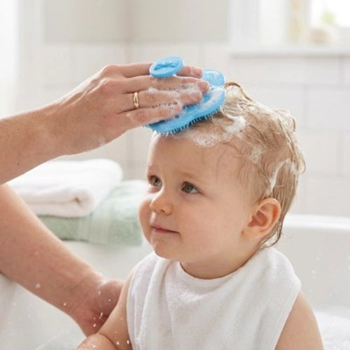 Brosse cheveux bébé bleue utilisee pendant le shampooing sur un enfant avec une serviette autour du cou