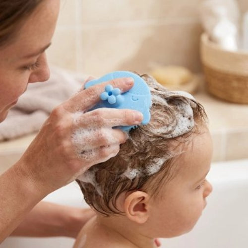 Brosse cheveux bébé bleue utilisee pour laver les cheveux avec de la mousse