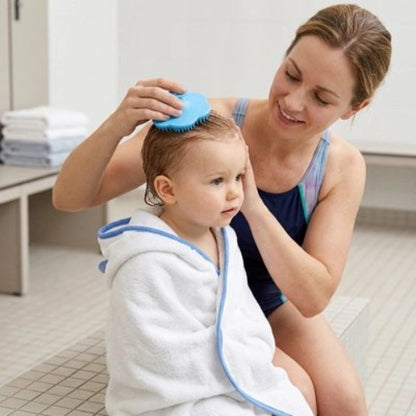 Brosse cheveux bébé bleue utilisee sur un enfant portant un peignoir blanc 
