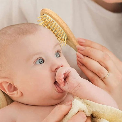 Brosse cheveux bébé en bois passant sur la tete d un bebe qui suce son pouce