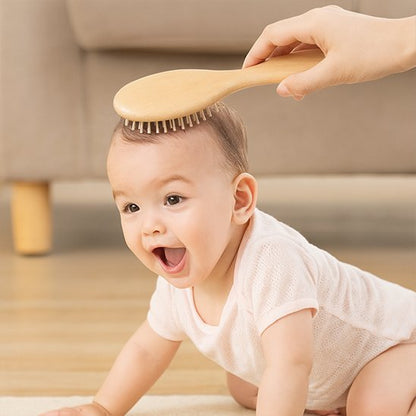 Brosse cheveux bébé en bois utilisee sur un bebe a quatre pattes