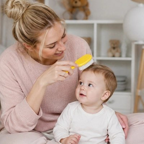 Brosse cheveux bébé jaune utilisee par une maman pour brosser les cheveux de son enfant