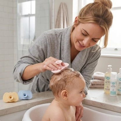 Brosse cheveux bébé rose utilisee par une maman sur les cheveux mouilles de son enfant dans une baignoire blanche