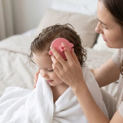 Brosse cheveux bébé rose utilisee sur les cheveux mouilles avec une serviette blanche autour des epaules