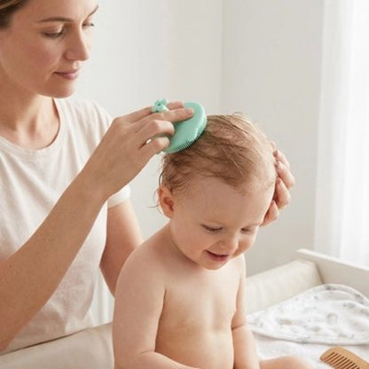 Brosse cheveux bébé verte utilisee par une femme pour brosser les cheveux de bebe