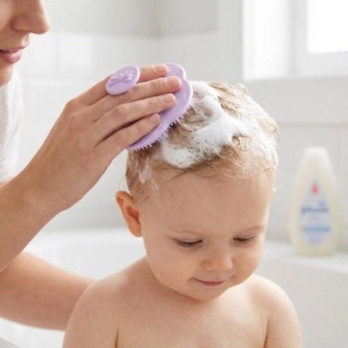 Brosse cheveux bébé violette utilisee pour laver les cheveux couverts de mousse