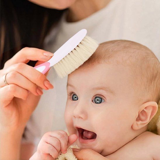 Brosse cheveux pour bébé a manche rose passant sur la tete d un bebe souriant