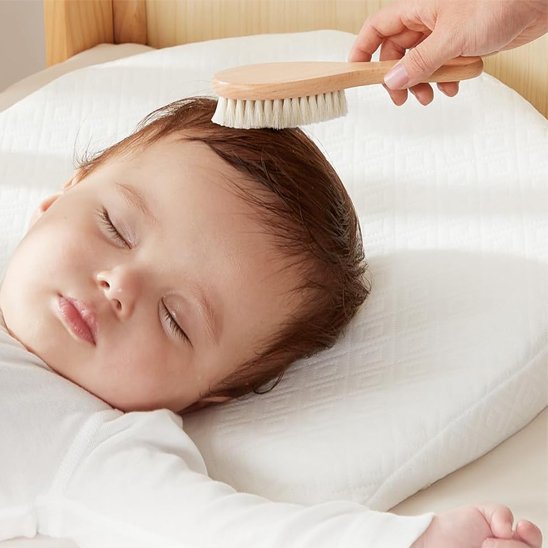 Brosse cheveux pour bébé a poils clairs utilisee sur les cheveux du nourrisson endormi