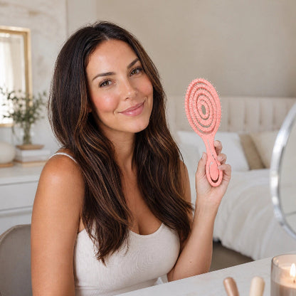 Brosse pour cheveux boucles rose tenue par une femme aux cheveux longs