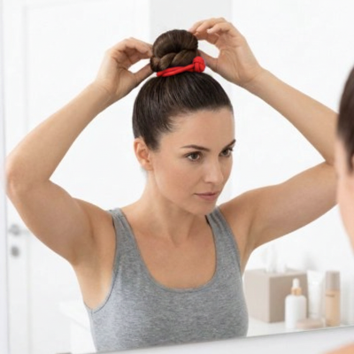 Élastique cheveux rouge femme coiffant son chignon devant un miroir 