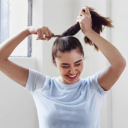 Élastiques  pour cheveux marron utilises par une femme pour attacher ses cheveux en queue de cheval haute