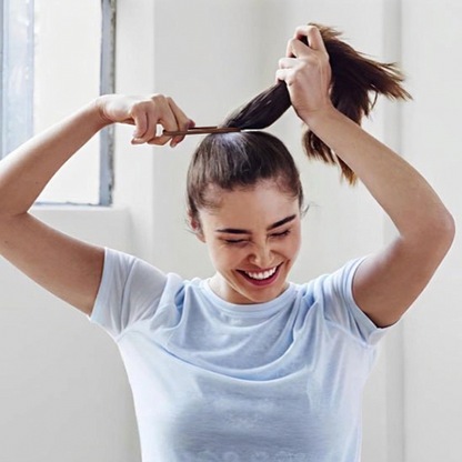 Élastiques  pour cheveux marron utilises par une femme pour attacher ses cheveux en queue de cheval haute