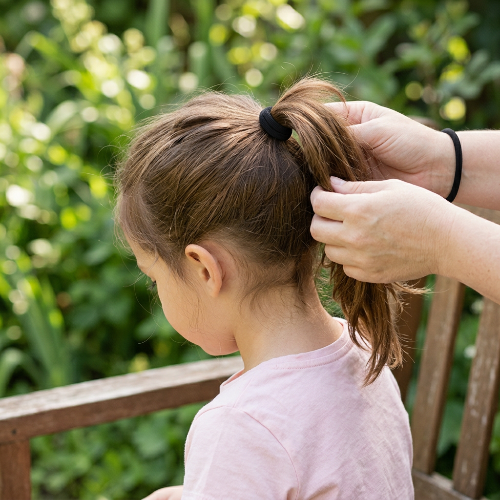 Élastiques pour cheveux noirs sur la queue de cheval d une petite fille dans un jardin