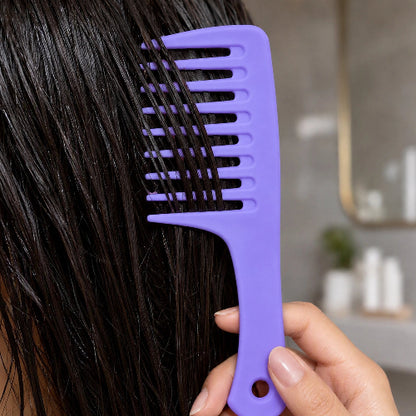Peigne à dents larges violet en gros plan dans des cheveux bruns mouilles