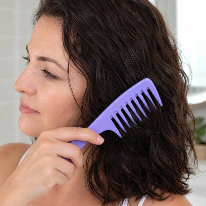 Peigne à dents larges violet utilise par une femme sur ses cheveux bruns ondules