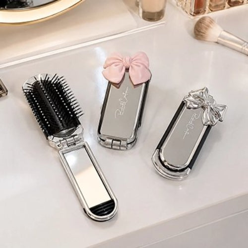 Peigne cheveux femme pliant avec miroir et modeles fermes a noeuds rose et argente sur une coiffeuse