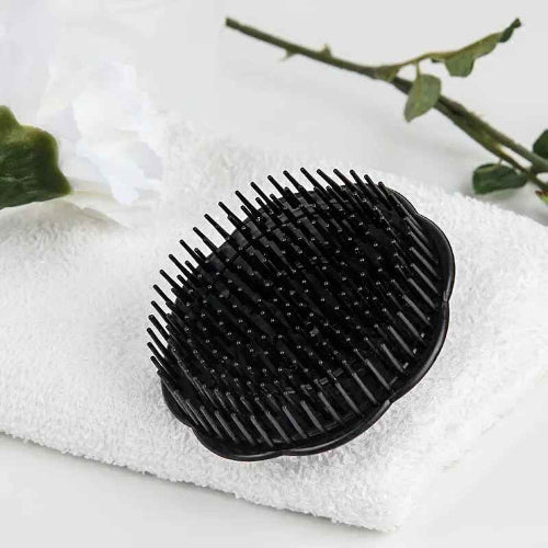 Peigne noir rond avec dos brillant et poignee courbee pose sur une serviette blanche