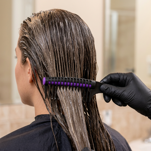 Peigne professionnel noir violet passe dans une meche de cheveux avec coloration en vue rapprochee de trois quarts arriere