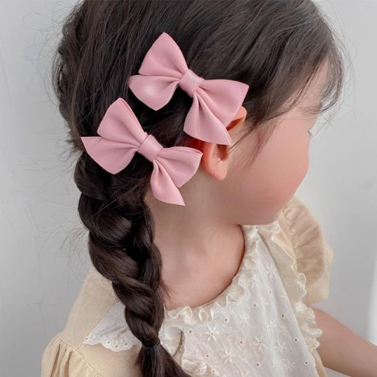 pince-à-cheveux-fillette-avec-tresse-et-deux-noeuds-roses-portant-robe-beige-elegante