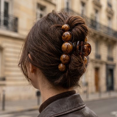 Pince-cheveux-a-grosses-perles-marron-vue-de-dos-chignon-elegant-maintenu-dans-une-rue-parisienne