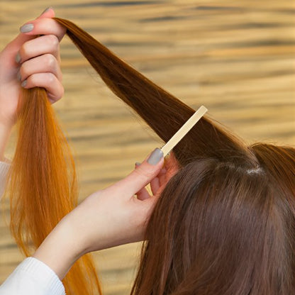 Pinces à cheveux crocodile dorees utilisees pour separer une meche de cheveux bruns