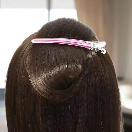Pinces à cheveux crocodile pince rose maintenant une meche brune relevee a arriere de la tete