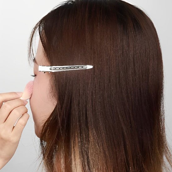 Pinces crocodiles argentees sur cheveux bruns pour degager le visage pendant le maquillage