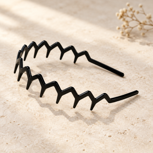 Serre tête chic noir en zigzag presente seul sur une surface beige