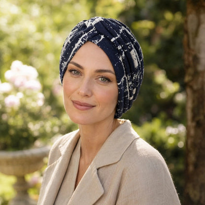 Turban femme  bleu marine a motifs blancs porte avec une veste beige dans un jardin