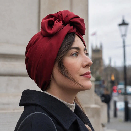 Turban femme bordeaux avec noeud volumineux vu de profil en ville