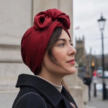Turban femme bordeaux avec noeud volumineux vu de profil en ville