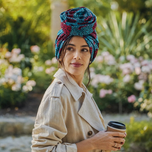 Turban pour femme bleu et rouge porte dans un jardin avec un gobelet en main